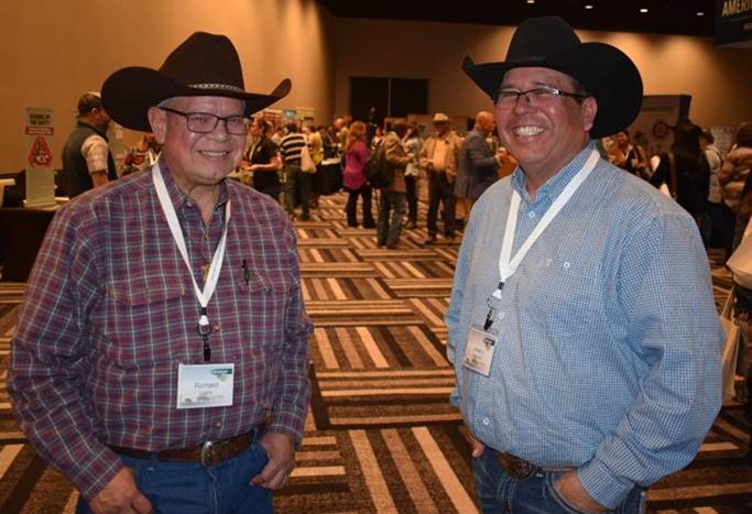 Two people standing facing toward camera while smiling